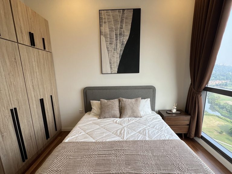 Bilik tidur utama menunjukkan almari tiga pintu kayu oak cerah di sebelah katil dan meja sisi katil