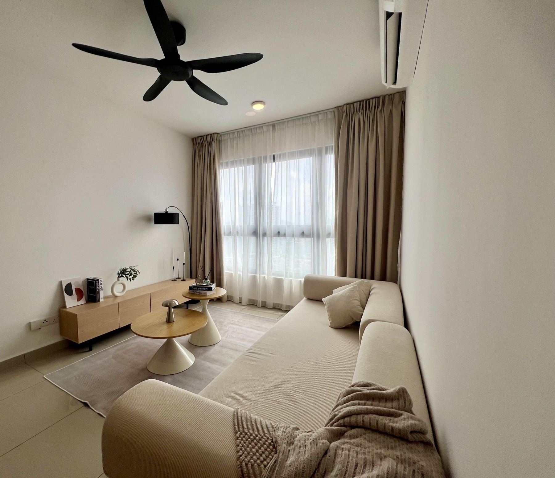 Wide view of the living room with ceiling fan and full-height curtains